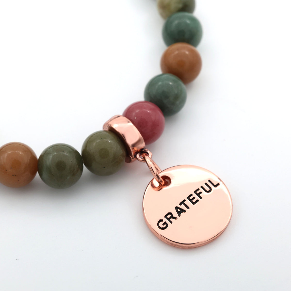 Necklace with multicolored beads and a rose gold 'GRATEFUL' charm on a white background