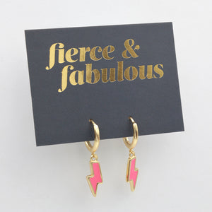 Pink lightning bolt shaped huggies dangle earrings presented on a grey card with gold 'Fierce & Fabulous' writing.