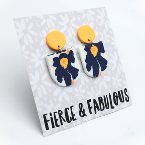 Earrings with blue floral design and yellow accents on a 'Fierce & Fabulous' card.