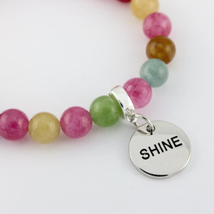 Multicolored beaded bracelet with a silver 'SHINE' charm on a white background