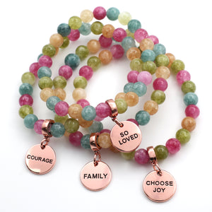 Multicolored beaded bracelets with rose gold charms on a white background