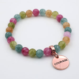 Multicolored beaded bracelet with a 'COURAGE' charm on a white background