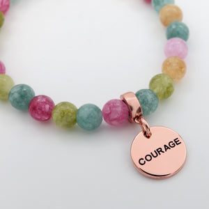 Multicolored beaded bracelet with a rose gold 'COURAGE' charm on a white background