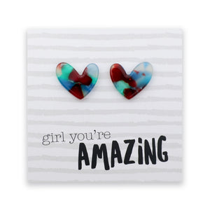 A pair of heart-shaped stud earrings with a marbled swirl pattern of red, blue, and green, displayed on a white card with the text 'girl you're AMAZING' printed on it.