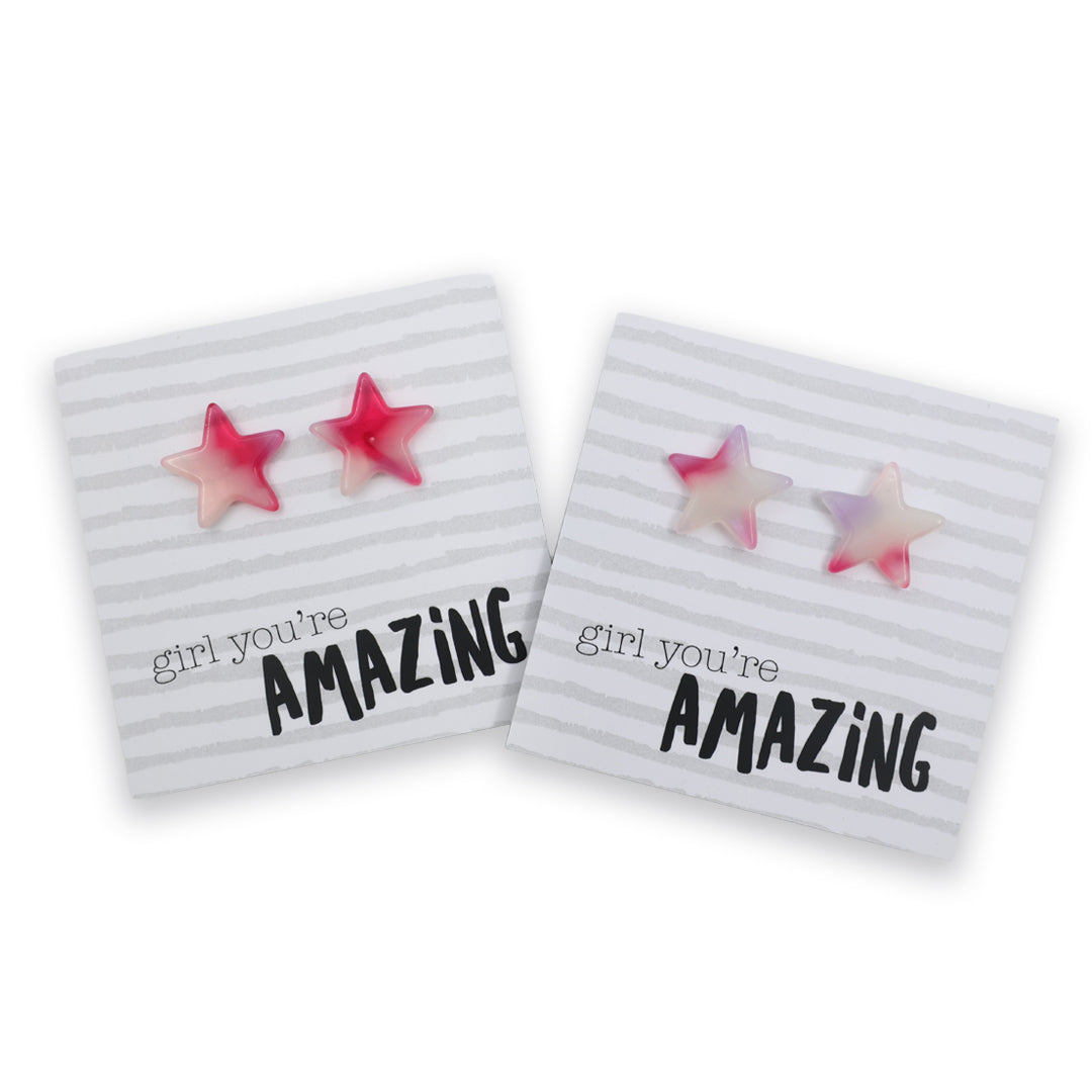 Two pink gradient star-shaped stud earrings displayed on white striped cards with the text 'girl you're AMAZING'.