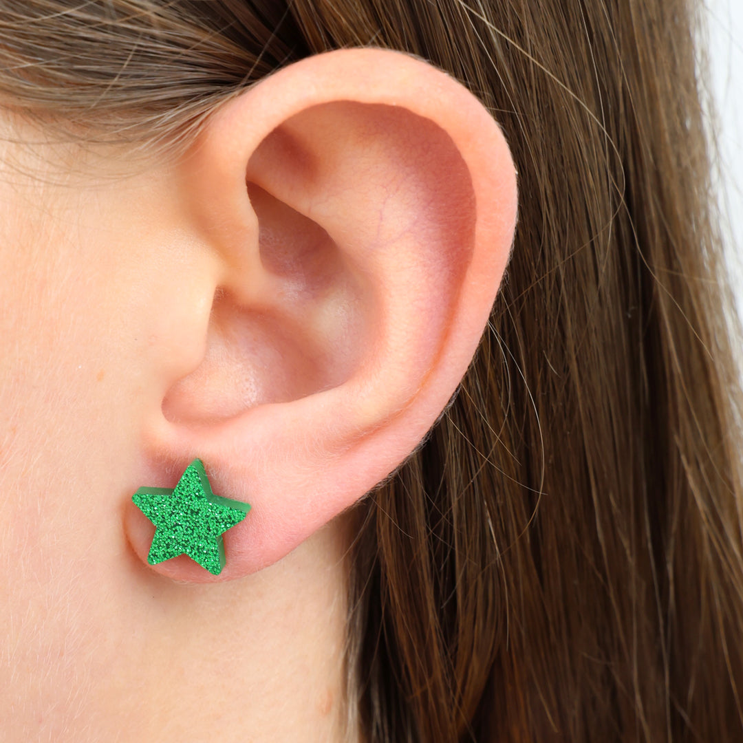 Green glitter star earirng in girls ear.