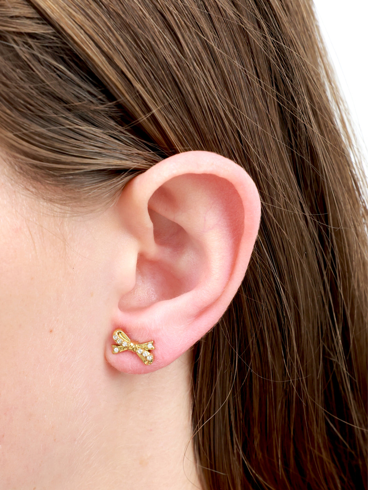 Gold bow earring with gems  in ear 