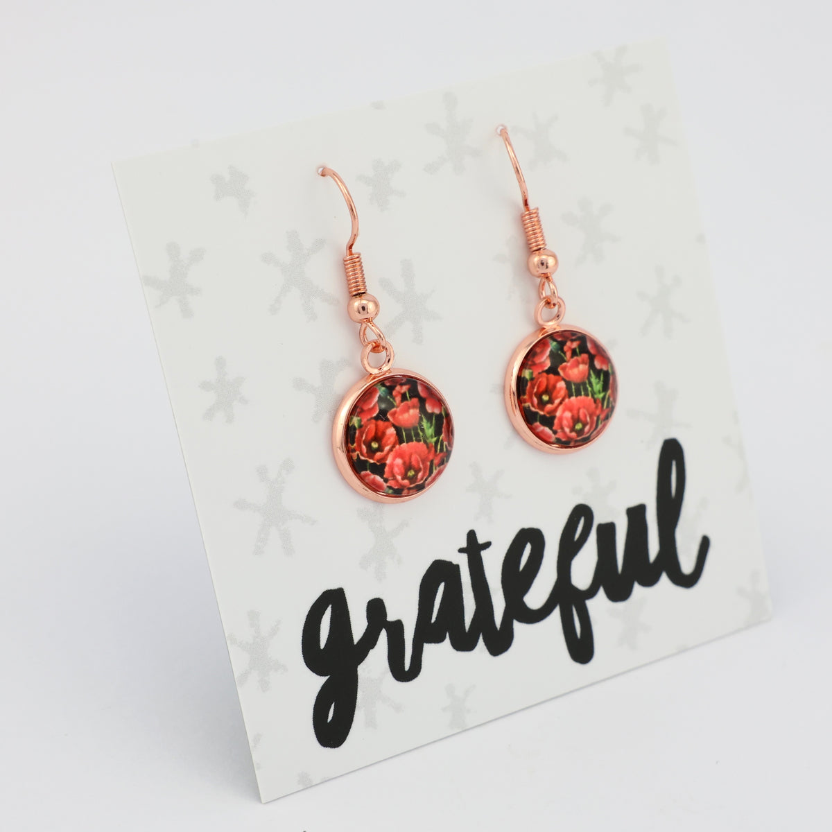 Rose gold floral earrings on a 'grateful' card with a white background