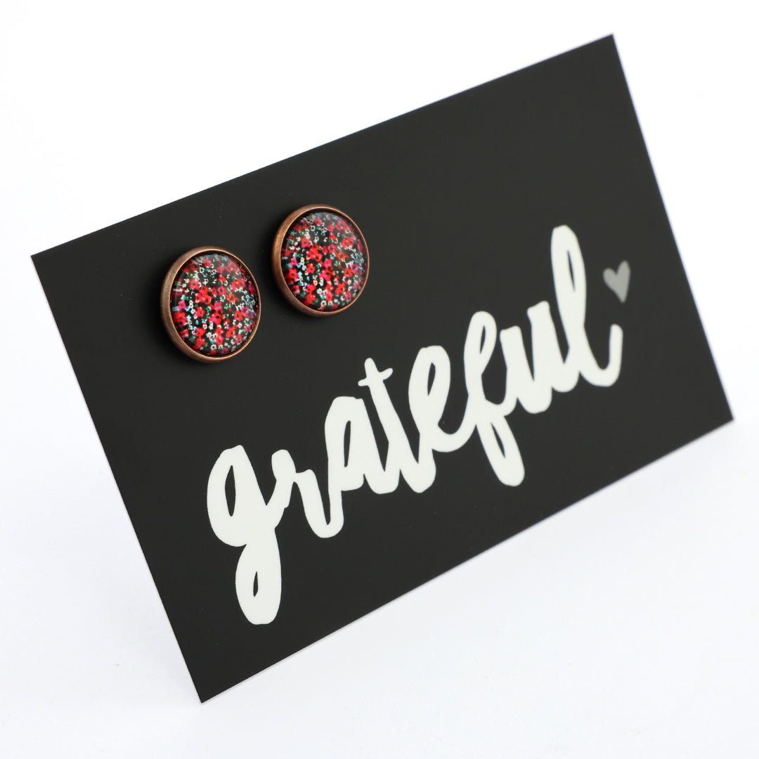 Round earrings with a colorful pattern on a black card with 'grateful' text.