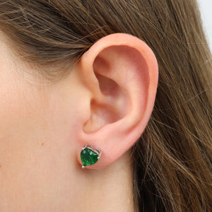 Close-up of an ear wearing a green gemstone earring with a blurred background