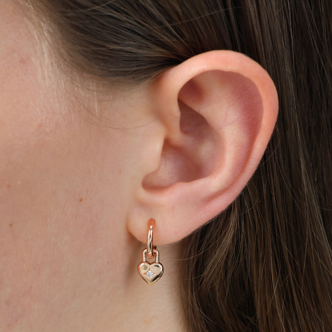 Close-up of an ear wearing a gold heart-shaped earring.