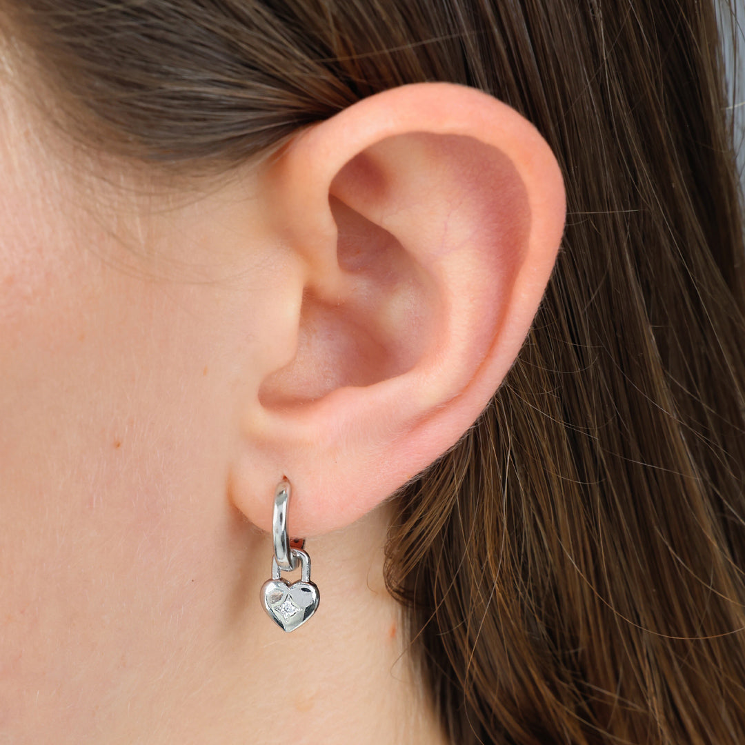 Silver heart earrings in ears