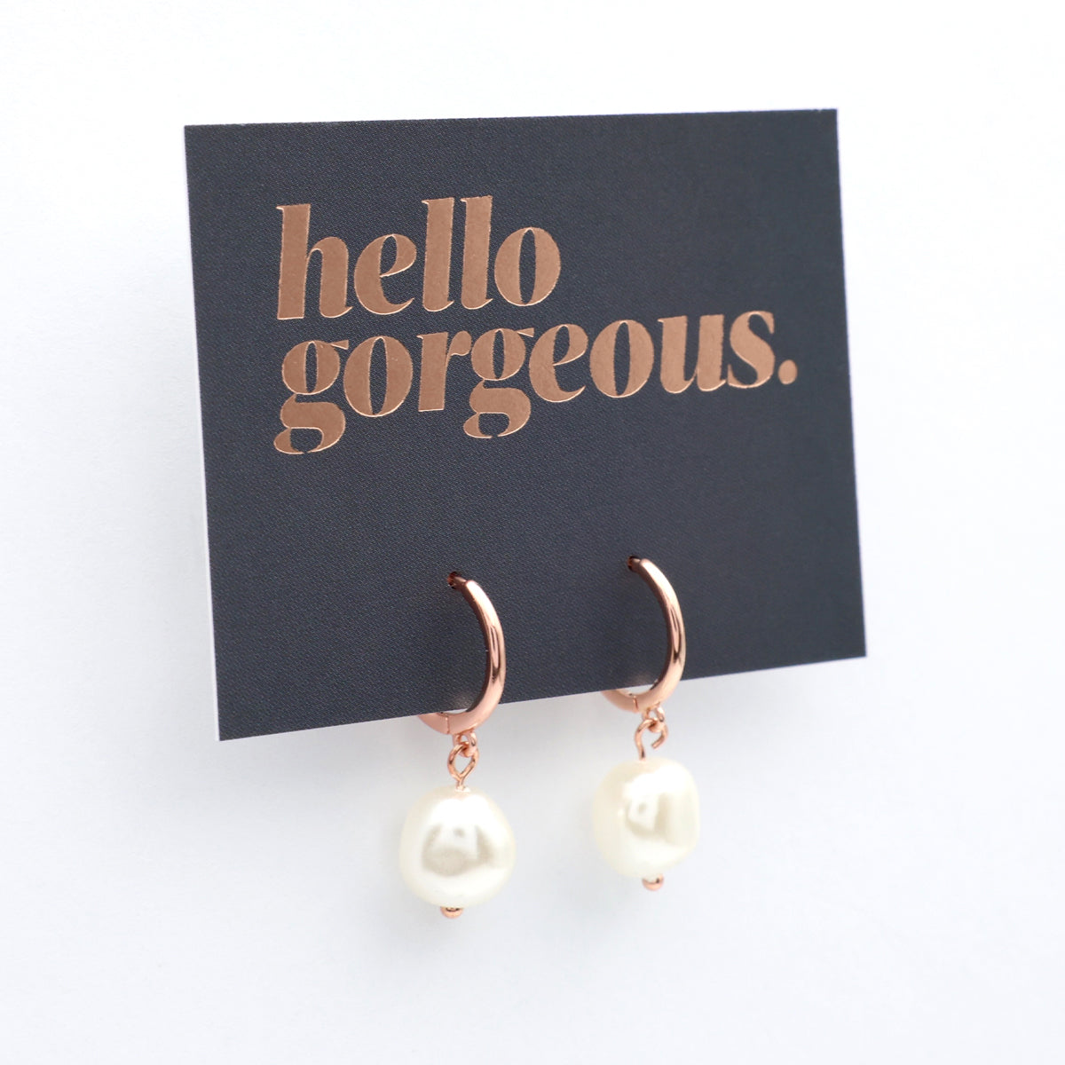 Rose gold earrings with pearl drops on a 'hello gorgeous' card.