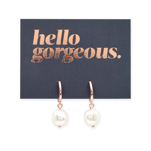 Rose gold earrings with white pearls on a card that says 'hello gorgeous' on a white background