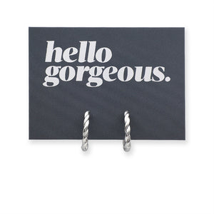 Silver twisty hoops on a grey card that has silver writing saying "Hello Gorgeous" on a white background