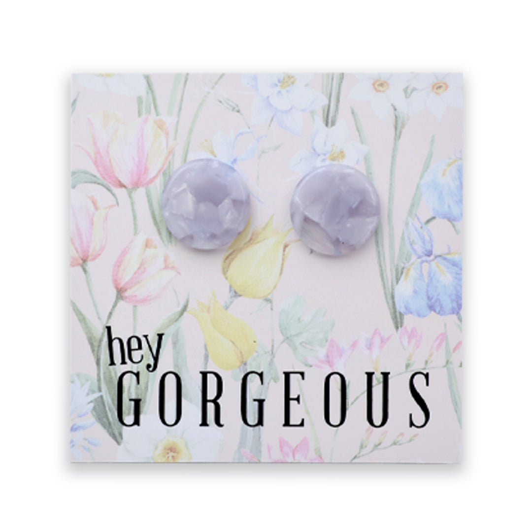 A pair of round, faceted lavender gemstone stud earrings displayed on a square floral backing card with the text 'hey GORGEOUS'.