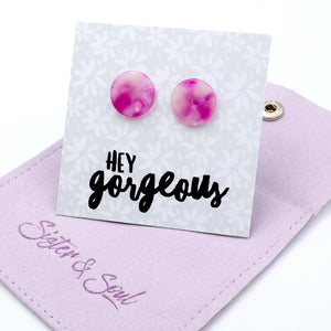 Pink and purple marbled round stud earrings displayed on a white floral backing card that reads 'HEY gorgeous', resting on a lavender fabric pouch with ' Sister & Soul'.