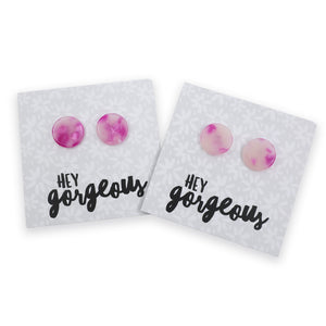 Two round stud earrings with pink and white marbled resin, displayed on white backing cards with the text 'HEY gorgeous'.