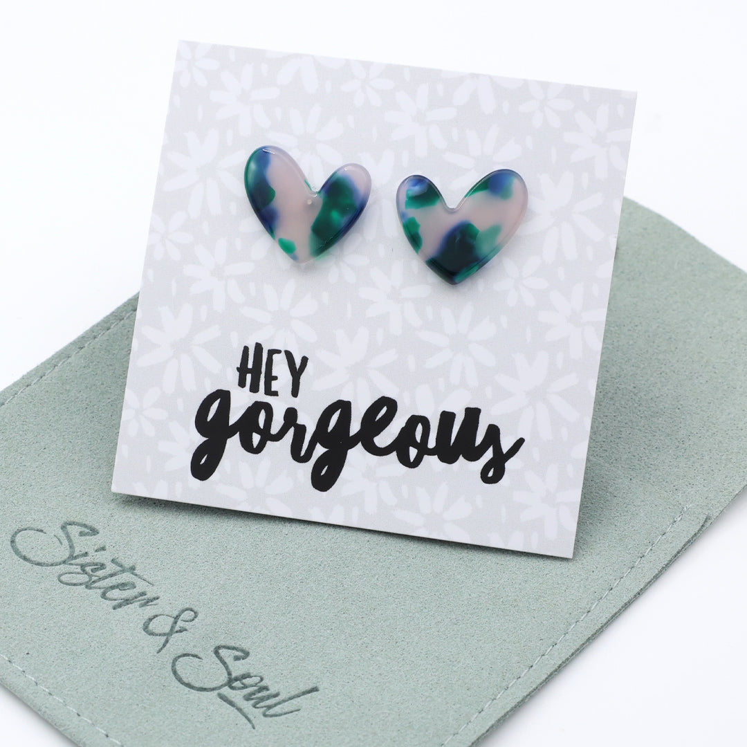 Heart-shaped earrings on a card with 'hey gorgeous' text on a sage pouch