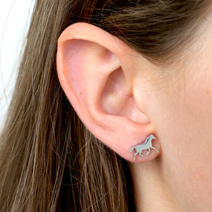 Close-up of an ear wearing a silver horse-shaped earring 