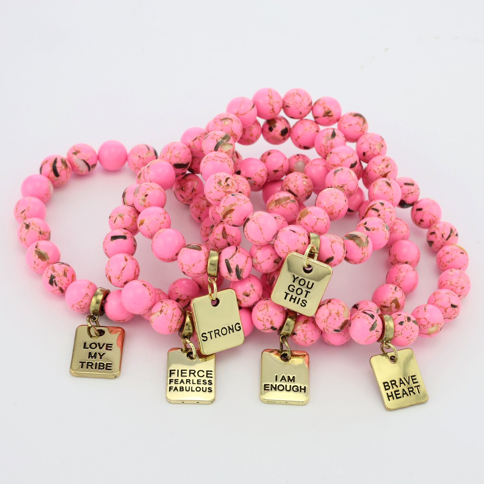 Pink beaded bracelet with gold charm tags on a white background