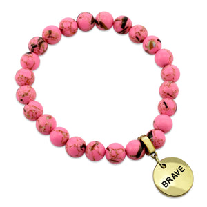 A collection of pink bead bracelets with vintage gold charms featuring words of courage and strength.