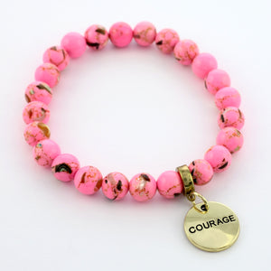 A collection of pink bead bracelets with vintage gold charms featuring words of courage and strength.