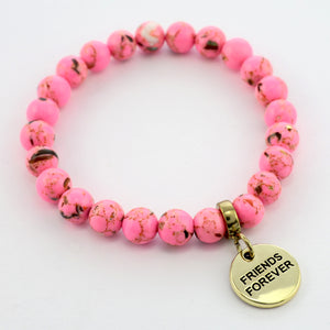 A collection of pink bead bracelets with vintage gold charms featuring words of courage and strength.