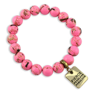 Pink beaded bracelet with a gold tag on a white background