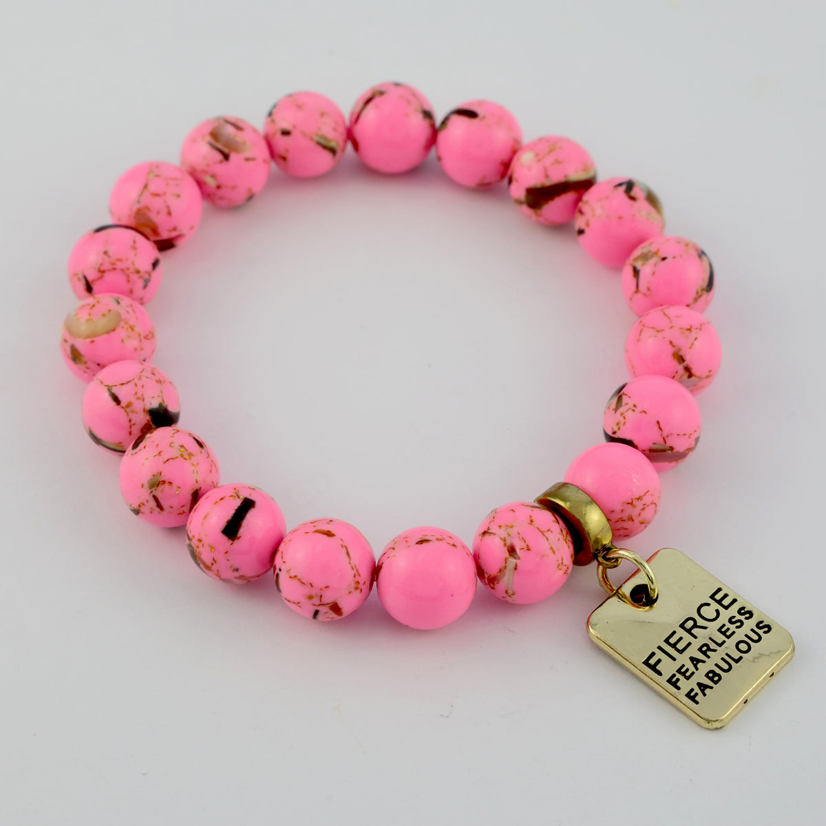 Pink beaded bracelet with a gold tag, reading Fierce Fearless Fabulous on a white background