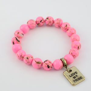 Pink beaded bracelet with a gold 'Love My Tribe' charm on a white background