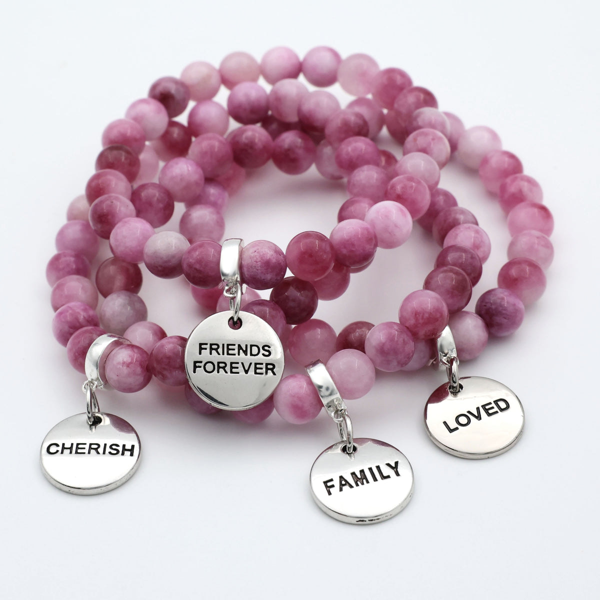 Pink beaded bracelets with silver charms on a white background