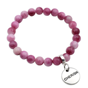 Pink beaded bracelet with a silver charm displaying the word 'CHERISH'.