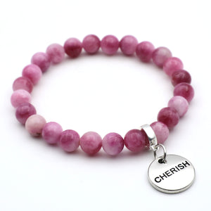 Pink beaded bracelet with a silver 'CHERISH' charm on a white background