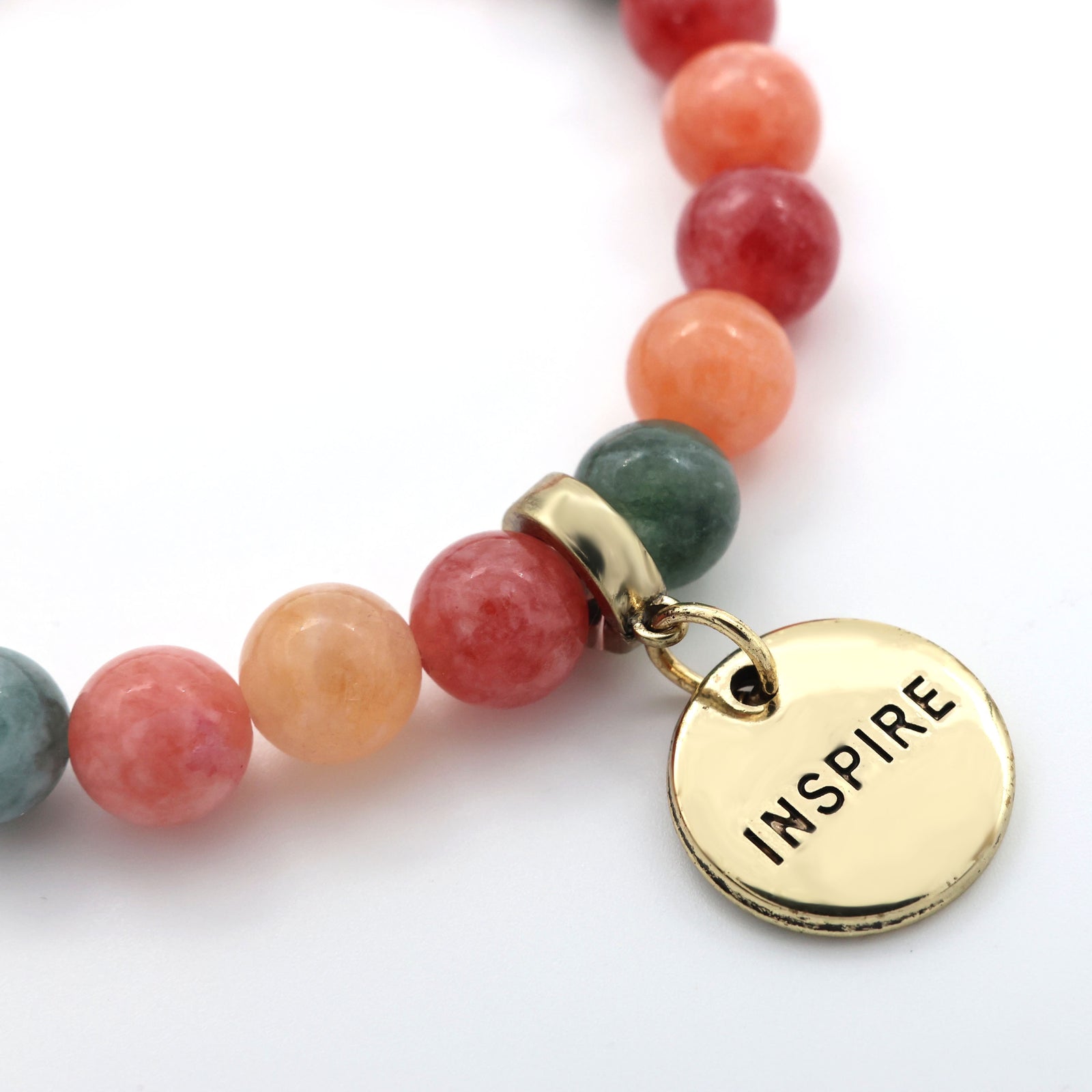 Stack of multicolored beaded bracelets with gold charm tags on a white background