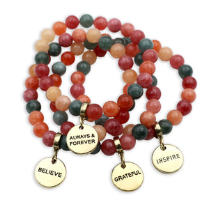 Stack of multicolored beaded bracelets with gold charm tags on a white background