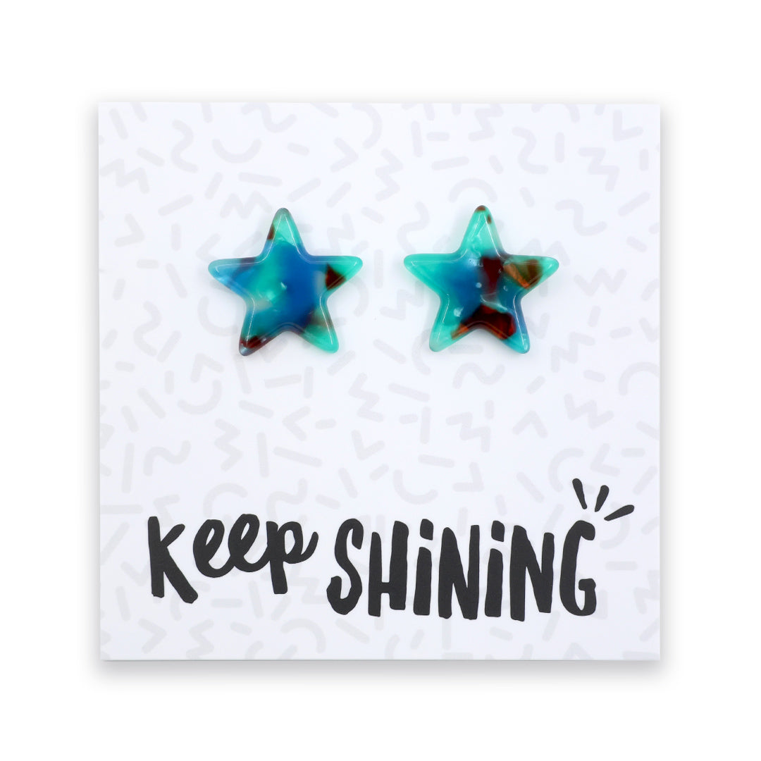 Two star-shaped stud earrings with a marbled blue, teal, and dark brown pattern, displayed on a white card that reads 'Keep SHINING'.