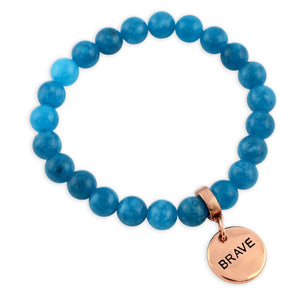 Blue beaded bracelet with a rose gold charm labeled 'BRAVE' on a white background