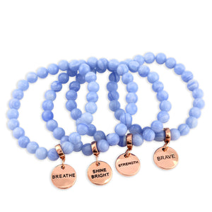 Set of blue beaded bracelets with rose gold charms on a white background