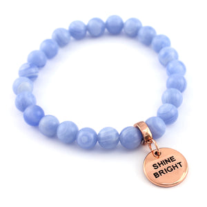 Blue beaded bracelet with a rose gold charm on a white background