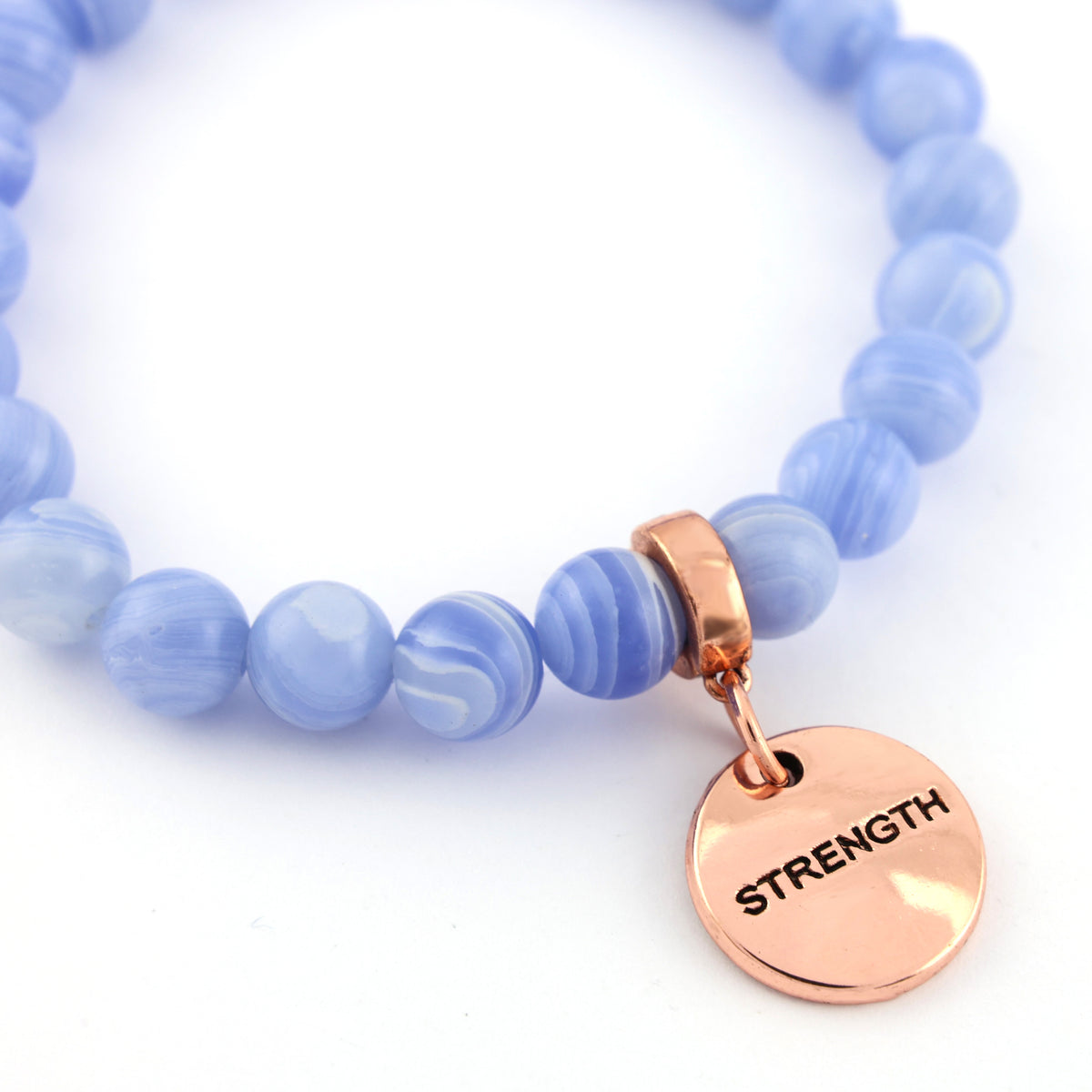 Blue beaded bracelet with a rose gold 'STRENGTH' charm on a white background