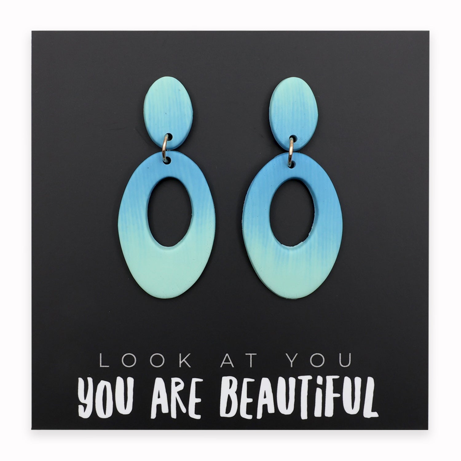 Blue earrings on a black card with motivational text