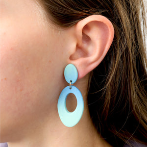 Close-up of a person wearing light blue oval earrings.
