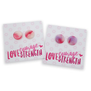 Two pairs of round stud earrings displayed on white backing cards with pink floral patterns and the words 'courage LOVESTRENGTH'. The left pair is pink and peach, and the right pair is pink and purple.