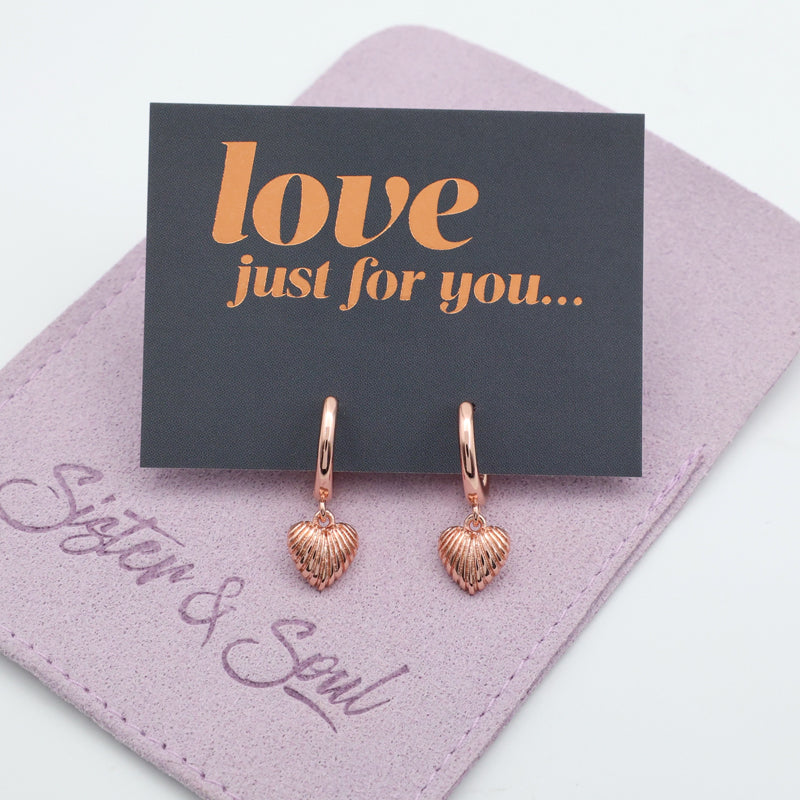 Rose gold heart-shaped earrings on a 'love just for you' card with a purple card holder.