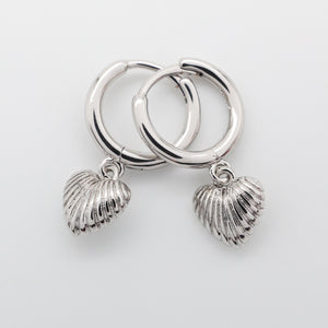 Silver hoop earrings with shell charms on a light gray background