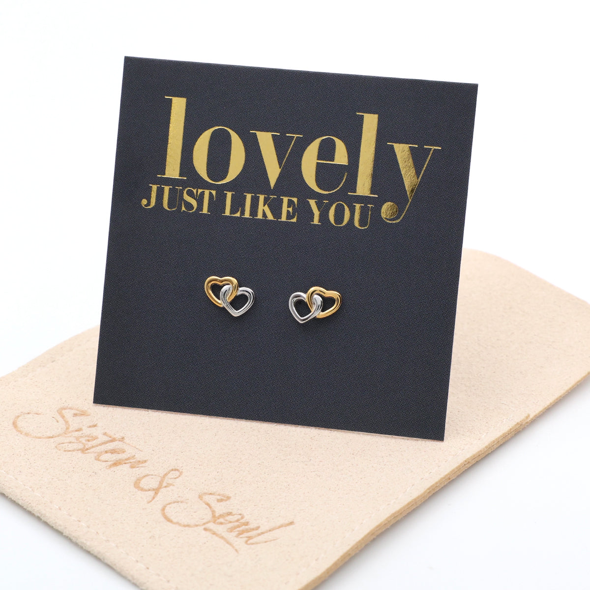 Heart-shaped earrings on a 'lovely JUST LIKE YOU' card with a beige pouch underneath.