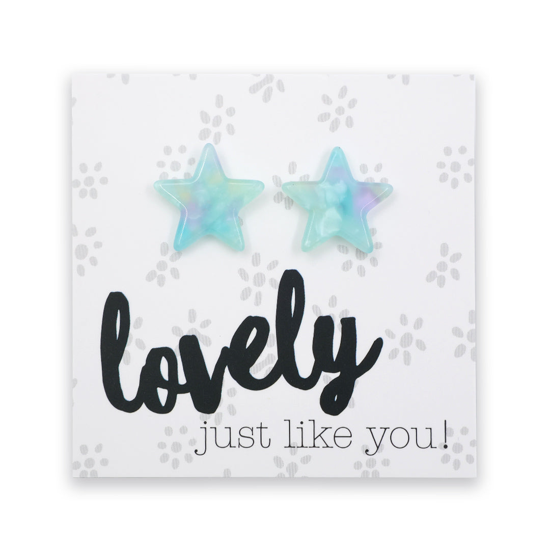 A pair of star-shaped stud earrings with a light blue and purple iridescent finish, displayed on a white square card that reads 'lovely just like you!' in black script.