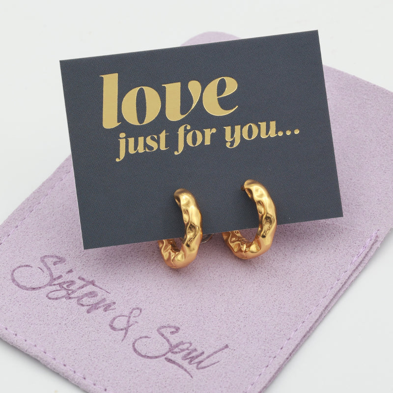 Gold hoop earrings on a love just for you card on a purple pouch