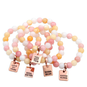 Set of colorful beaded bracelets with inspirational charms on a white background